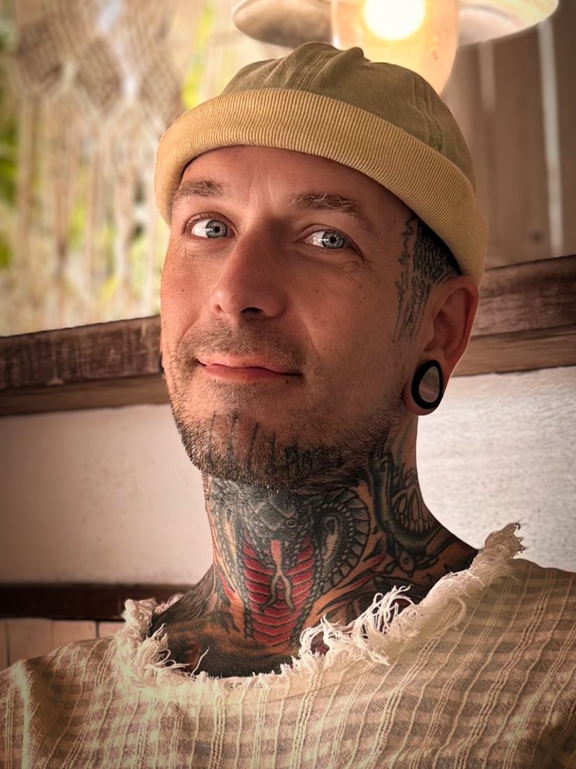 Rich D'Amaru, smiling, in a knit cap under a warm hanging lamp
